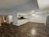 Modern open-concept apartment with sleek wood flooring, featuring a spacious living area connected to a stylish kitchen bar counter.