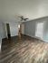 Charming living room with warm wood-style flooring, fresh gray walls, and a bright patio door, ideal for relaxation and natural light.