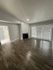 Beautifully lit living room with elegant wood flooring, featuring a cozy fireplace and large windows with shutters for natural light.