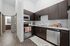 Modern kitchen with sleek dark wood cabinets, stainless steel appliances, and a cozy earth-toned rug, offering a stylish space for culinary creativity.