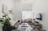 Modern, sunlit living room with sleek black leather sofa, stylish wall art, and minimalistic decor.