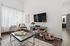 Chic and inviting living room with modern decor, featuring a cozy seating area, large TV, and abundant natural light.