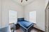 Bright bedroom with modern furniture, featuring a sleek blue bed and chic workspace with ample natural light.