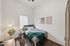 Inviting bedroom with modern decor, featuring a cozy bed, stylish wall art, and a sleek desk area bathed in natural light.
