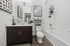 Modern bathroom with sleek dark wood vanity, elegant mirror, bright white bathtub, and stylish decor featuring accent art and cozy towels.