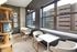 Bright and modern reading nook with stylish chairs and tables, overlooking city views through large windows.