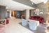 Chic modern living space with plush red and blue seating, stylish wall art, and warm wooden flooring offering a cozy ambiance.