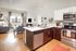 Modern open-plan kitchen and living area with sleek stainless steel appliances and stylish decor, perfect for comfortable urban living.