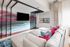 Chic living room featuring a modern sectional sofa with vibrant pillows, a stylish abstract accent wall, and a wall-mounted flat screen TV.