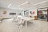 Modern conference room featuring sleek white chairs around a large table, chic lighting, and stylish artwork, ideal for professional meetings.