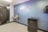 Modern fitness area with motivational 'Don't Quit' neon sign and stylish blue wallpaper, featuring a water station and sleek equipment for an energizing workout environment.