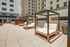 Luxurious outdoor terrace featuring modern cabanas with plush seating, surrounded by high-rise buildings and urban tranquility.
