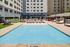 Elegant outdoor pool area with sun loungers and modern apartment buildings, perfect for relaxation and leisure.