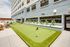 Modern apartment exterior featuring a vibrant mini-golf putting green, perfect for outdoor leisure and relaxation.