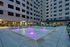 Modern apartment courtyard featuring a vibrant water fountain with purple lights, surrounded by comfortable seating and relaxing lounges.