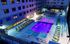 Luxurious apartment courtyard featuring an illuminated swimming pool, comfortable lounge chairs, and a relaxing atmosphere.
