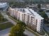 Modern multi-story apartment complex with striking architectural design, nestled in a lush suburban setting with ample greenery and well-maintained surroundings.
