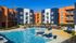 Vibrant apartment complex with modern architecture featuring a refreshing outdoor pool surrounded by comfortable lounge chairs and lush greenery.