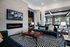 Contemporary lounge room featuring stylish geometric carpet, plush seating, wall-mounted TV, and a modern fireplace.