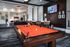 Luxurious apartment amenity space featuring a vibrant billiards table, modern seating area, and wall-mounted TV for entertainment.