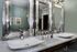 Luxurious modern bathroom with double sinks, elegant silver mirrors, and stylish green walls.