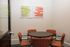 Cozy meeting room with vibrant orange chairs around a round table and colorful wall art adding a touch of modern elegance.