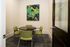 Chic meeting room with modern art, a sleek round table, and vibrant green chairs for a stylish, professional space.