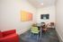 Modern conference room with vibrant chairs, sleek table, colorful wall art, and a mounted screen, perfect for productive meetings.