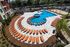 Luxurious outdoor pool area with vibrant orange lounge chairs, surrounded by lush greenery, perfect for relaxation and leisure.