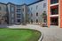 Modern apartment courtyard with chic lounging area, lush putting green, and contemporary architecture.