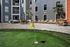 Modern apartment courtyard featuring a chic outdoor seating area, stylish sun loungers, and a vibrant mini golf green surrounded by palm trees.