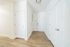 Bright apartment entryway featuring sleek wooden floors, crisp white doors, and modern lighting.