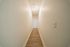 Bright and inviting hallway with elegant wood flooring leading to a spacious room, showcasing modern and minimalistic design.