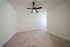 Bright and spacious bedroom with plush carpeting and a modern ceiling fan, perfect for relaxation.