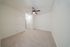 Bright, spacious room with plush carpeting, modern ceiling fan, and ample closet space.