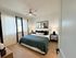 Inviting bedroom with modern decor, featuring a cozy bed, stylish pillows, and chic lamps, creating a serene retreat.