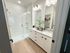 Elegant bathroom featuring a spacious glass-enclosed shower, dual granite sinks, and modern lighting fixtures.