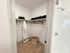 Elegant walk-in closet with spacious shelving, luxurious robe, slippers, and modern shower entry nearby.