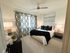 Elegant bedroom with a cozy ambiance, featuring modern decor, plush pillows, and a stylish ceiling fan.