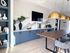 Chic modern kitchen with blue cabinets, elegant marble backsplash, and stylish pendant lighting over a wooden dining table.