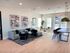 Modern living space with elegant decor, featuring a cozy seating area, striking abstract art, and ample natural light.