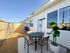 Charming outdoor patio with a dining set, vibrant plant, and children's play area, perfect for family gatherings.