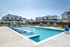 Inviting apartment complex with a sparkling swimming pool, surrounded by elegant homes and lush landscaping.