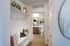 Chic apartment hallway with modern decor leading to a stylish bathroom, featuring elegant shelving and contemporary artwork.
