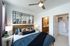 Elegant bedroom with modern decor, featuring a cozy king bed, stylish mirror, ceiling fan, and an inviting en-suite bathroom.