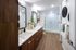 Elegant modern bathroom featuring dual sinks with sleek wooden cabinetry, large mirrors, and a spacious glass-enclosed shower.