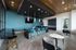 Chic modern lounge featuring a sleek bar with vibrant blue seating, elegant black marble surfaces, and warm wood accents under ambient lighting.