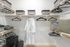 Immaculate walk-in closet with ample hanging space, elegant storage baskets, and a plush bathrobe, showcasing a blend of luxury and functionality.
