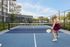 Lively pickleball court with residents enjoying the game, modern apartment building in the background and vibrant outdoor amenities.