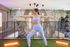 Modern fitness area with vibrant lighting featuring a person practicing yoga on artificial grass, surrounded by stylish decor and workout equipment.